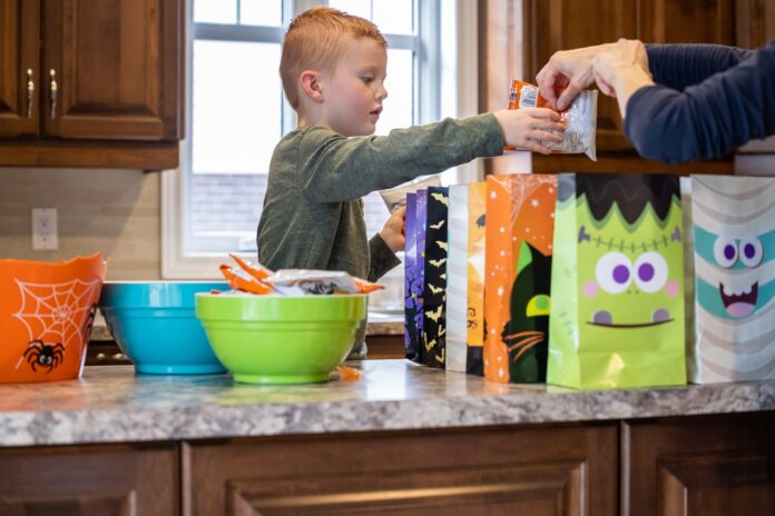 Cute Redhead Boy And Mother Preparing Halloween Candy Bags at Home